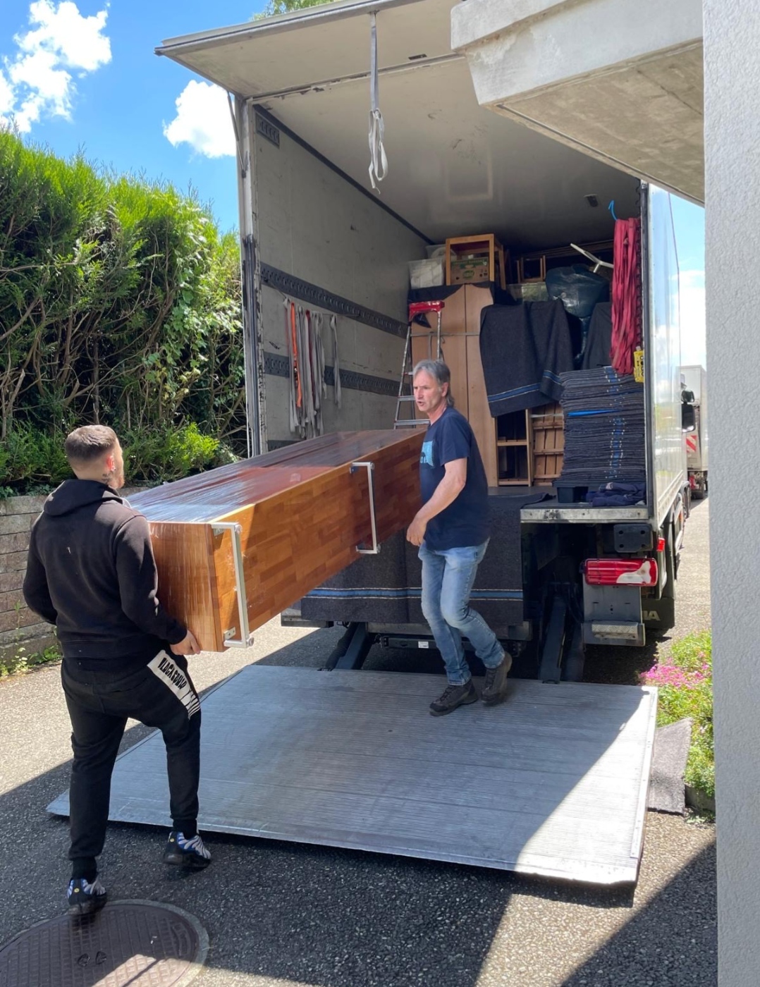 Équipe Moser déménageant un piano avec vue sur le lac Léman